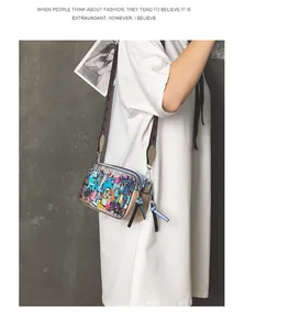 Detail of colorful graffiti camera bag with wide strap and tassel zipper on model
