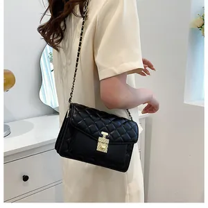 Detail of black quilted crossbody bag with gold chain strap on a model's waist