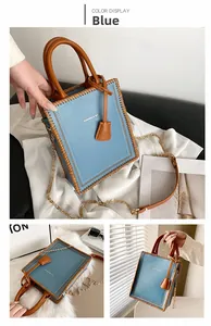 Detail of light blue tote bag with brown woven leather seams and gold chain strap