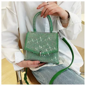 Detailaufnahme der funkelnden grünen Strass-Handtasche von einem Modell in weißem Outfit
