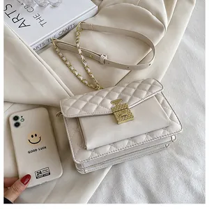 Detail of beige quilted shoulder bag with unique gold perfume bottle clasp and chain strap