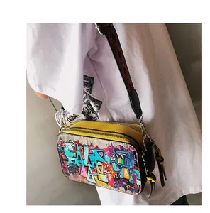 Detail of yellow camera bag with graffiti prints and colorful wide geometric strap