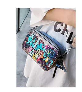Detail of trendy graffiti camera bag with colorful prints and blue leather tassel charm