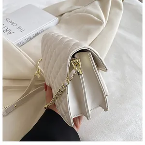 Side view detail of white quilted crossbody bag with gold chain strap and dual compartments