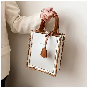 Detail of cream tote bag with brown woven edges and metallic chain strap
