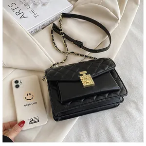 Detail of black quilted leather crossbody bag with gold perfume bottle clasp and chain strap