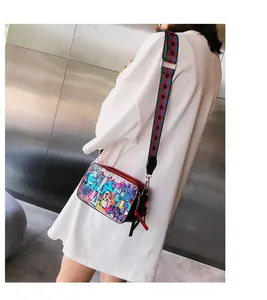 Detail of colorful graffiti camera bag with geometric patterned wide strap on a model