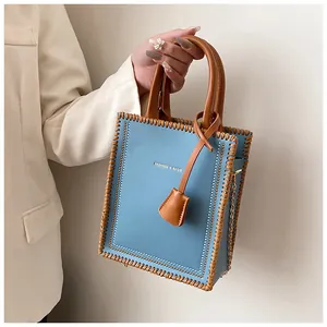 Detail of light blue tote bag with brown woven stitching and gold chain strap