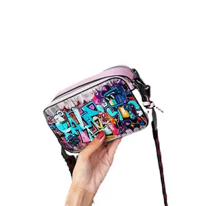 Pink graffiti camera bag with colorful cartoon prints and a wide woven shoulder strap