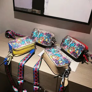 Graffiti style camera crossbody bags with colorful art prints and wide webbing straps