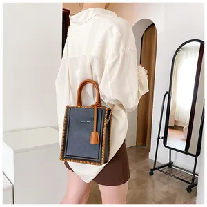 Detailed shot of dark blue tote bag with brown handles and elegant metal chain strap