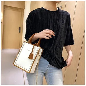 Lifestyle shot of white and brown crossbody tote bag with woven trim and metal chain