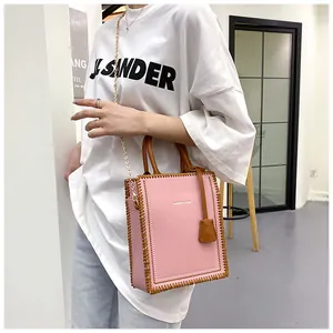 Pink tote bag with brown woven edges and golden chain strap shown on model style