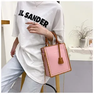 Detailed view of pink tote bag with brown whipstitch edges and golden chain strap