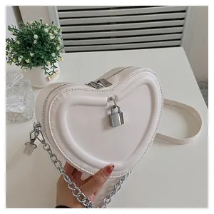 Detail of cream heart-shaped crossbody bag with silver hardware and chain strap