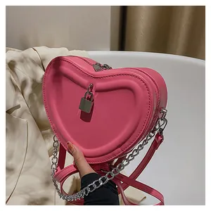 Detailed view of pink heart-shaped quilted handbag with silver lock and chain strap