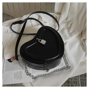 Detail of heart-shaped black leather handbag with silver lock and metal chain strap