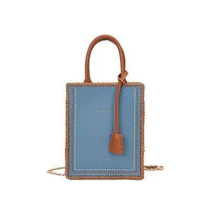 Light blue faux leather tote bag with brown woven edges and a gold chain strap