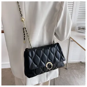 Détail du sac matelassé noir à motif de vagues avec boucle en perles et chaîne dorée