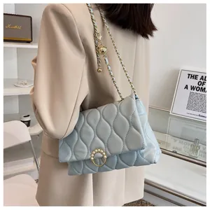 Détail du sac matelassé bleu clair avec boucle en perles et chaîne à boule dorée