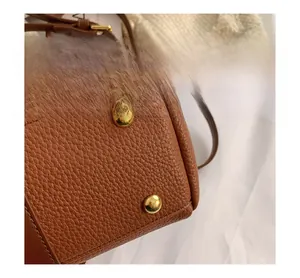 Détails des rivets dorés et texture du cuir grainé sur le fond du sac à main