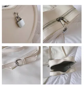 Detail view of cream heart-shaped crossbody bag with gold lock and adjustable strap