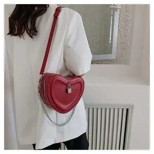 Detail of red heart-shaped crossbody bag with quilted pattern and metal lock charm