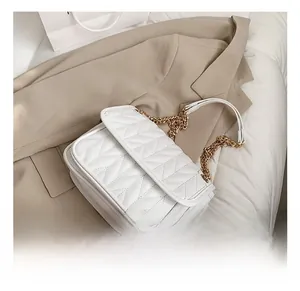 Detail of white quilted V-pattern faux leather bag with gold chain strap on blazer