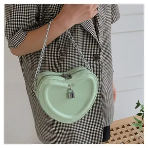 Detail of heart-shaped mint green quilted mini crossbody bag with silver chain strap