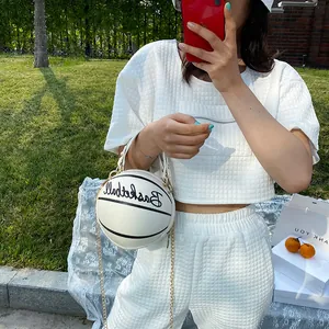 Sac à bandoulière blanc en forme de basket avec chaîne dorée sur fond de pelouse verte