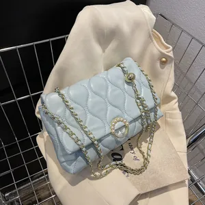 Sac bandoulière matelassé bleu clair avec chaîne et boucle perle sur cardigan