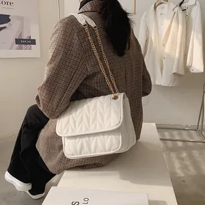 Chic white quilted shoulder bag with V-shaped stitching and gold chain strap in a lifestyle shot