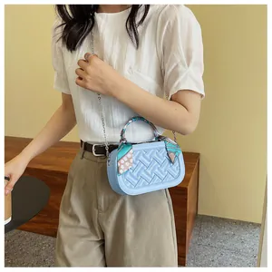Close-up of light blue crossbody bag with woven texture and scarf-wrapped handle detail