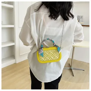 Detail of a bright yellow woven handbag featuring a decorative silk scarf on the handle
