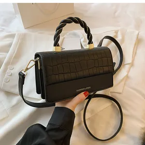 Detail of black faux leather handbag with crocodile pattern flap and twisted rope handle