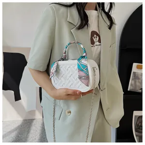 White mini crossbody bag with silk scarf handle detail and metal chain on model