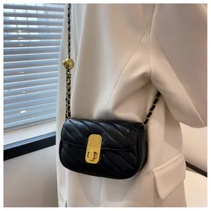 Détail du sac bandoulière matelassé noir avec chaîne dorée et décoration de boule en métal