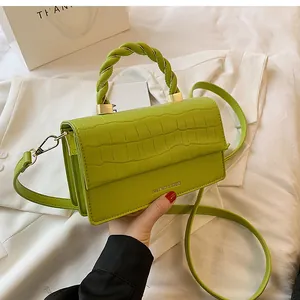 Detail of lime green handbag featuring crocodile texture and unique spiral twist handle