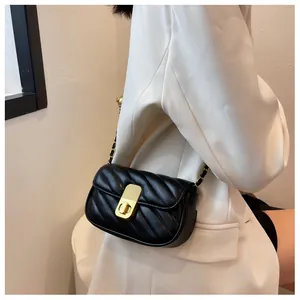 Détail du sac matelassé noir avec fermoir doré sur une veste de blazer blanc