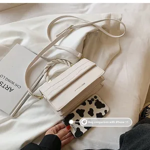 Chic beige square crossbody bag size comparison with an iPhone 11 on white fabric