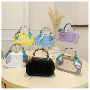 Detailed view of woven leather handbags with decorative silk scarves and metal chain straps