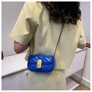 Détail du petit sac bandoulière en cuir bleu marine avec chaîne dorée et fermoir pivotant