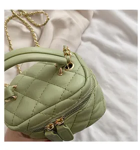 Close-up of light green quilted mini box bag with gold chain strap and leather handle