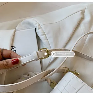 Detail of adjustable shoulder strap with gold buckle on white crocodile pattern handbag