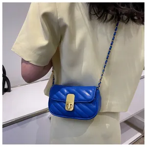 Détail du mini sac à bandoulière bleu matelassé avec chaîne dorée et fermoir pivotant