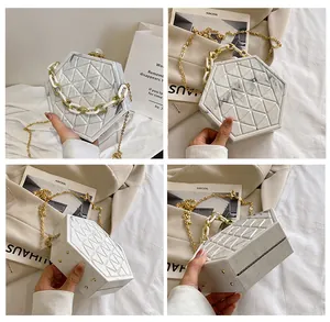 Detailopname van hexagonale harde koffer tas met wit marmerpatroon en kettingriem