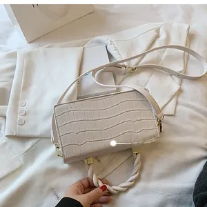 Detail view of white crocodile pattern crossbody bag with unique twisted handle and gold hardware