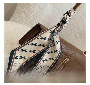Dettaglio borsa marrone texture coccodrillo con foulard di seta e fibbia oro
