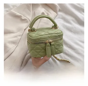 Detail view of small green quilted box bag with golden chain strap and double zipper