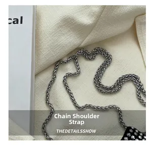 Gros plan sur la bandoulière chaîne argentée d'un sac seau noir orné de strass